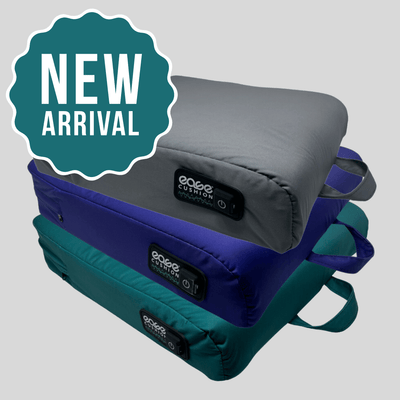 A stack of new Ease Cushion covers in gray, blue, and teal showcases its integrated handle and power button.
